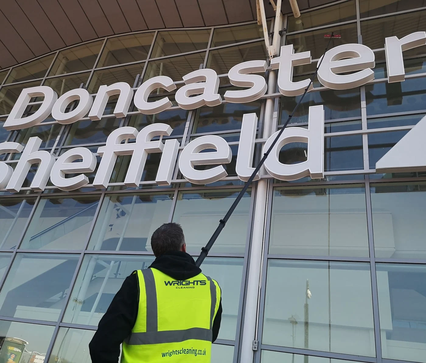 Wrights Cleaning operative in branded hi-vis cleaning airport glazing