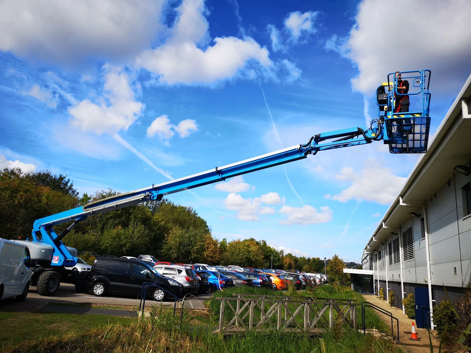 Cherry picker extended over a business park to reach high-level glazing