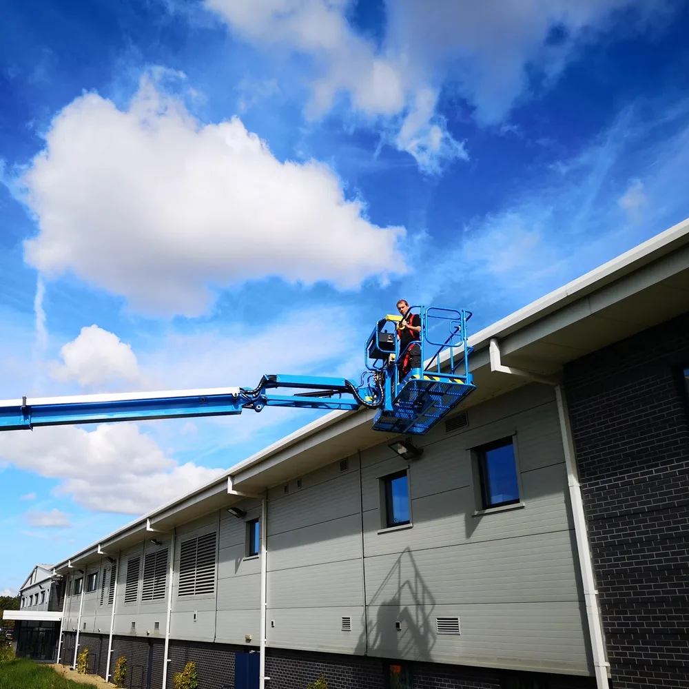 Operative in a cherry picker basket at the roofline of a commercial building