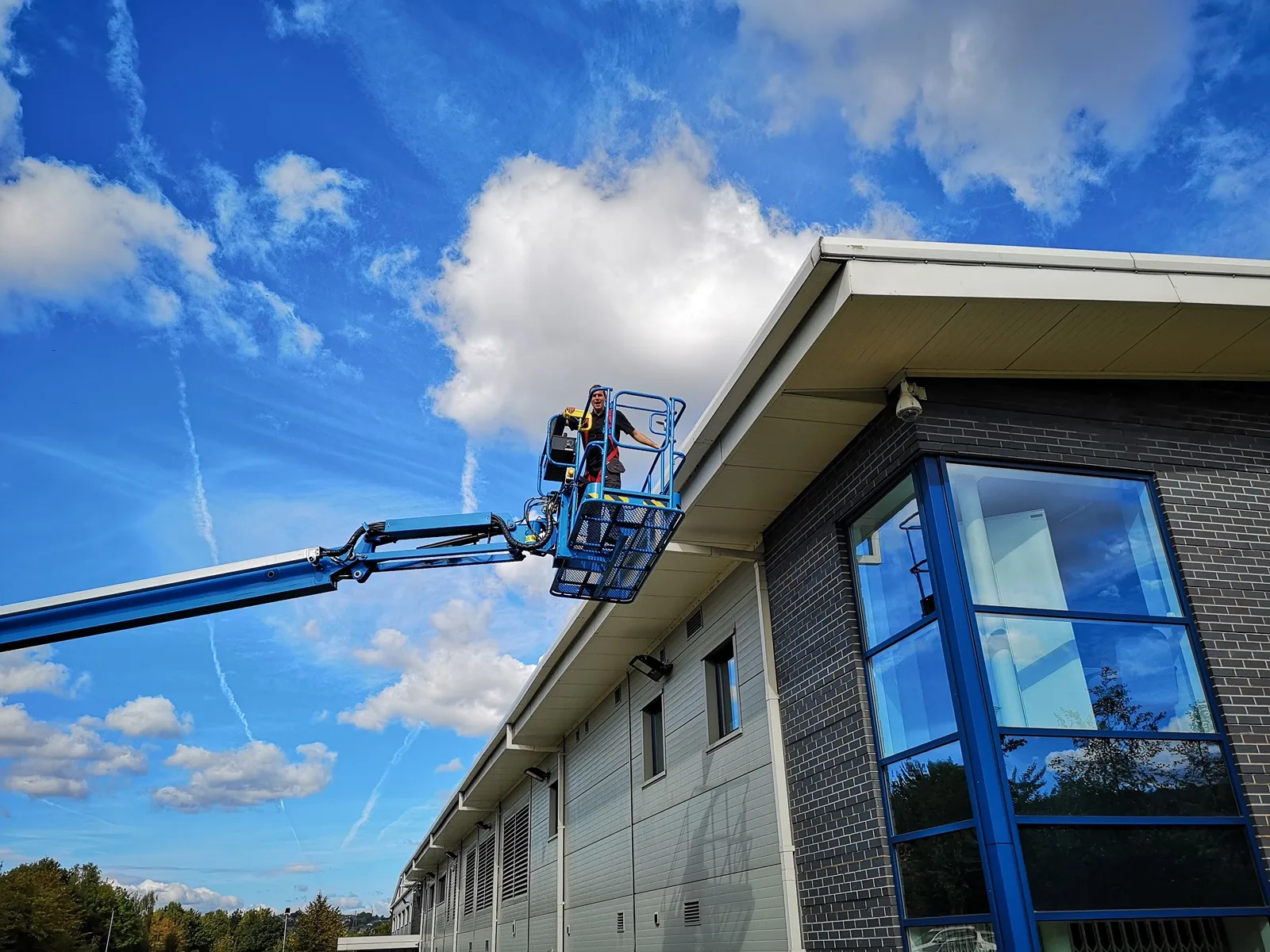 Cherry picker at the roofline of an office building with a glazed stairwell