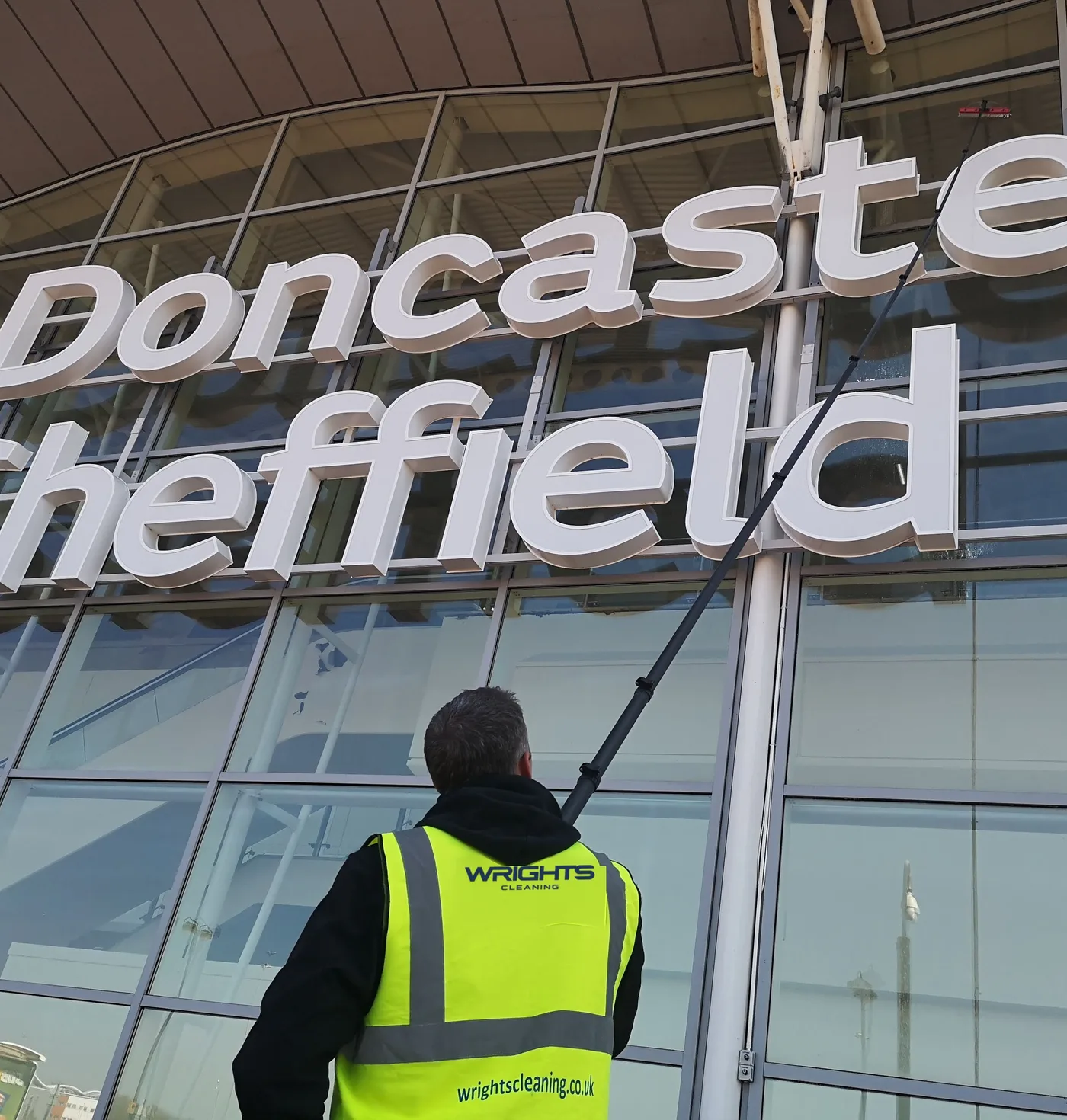 Wrights Cleaning operative cleaning the glazing at Doncaster Sheffield Airport with a water-fed pole