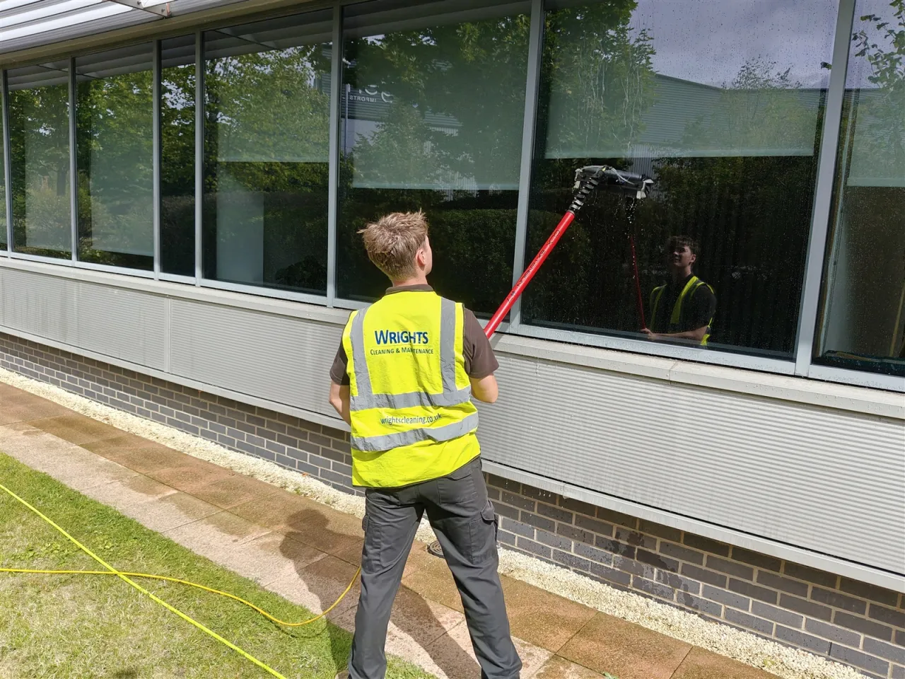 Office window cleaning: a Wrights Cleaning operative cleaning office glazing with a water-fed pole
