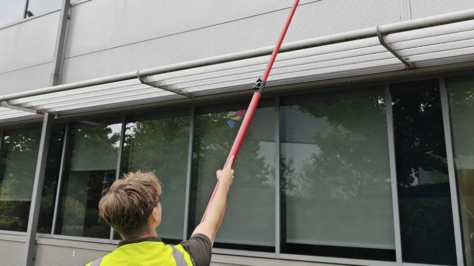 Operative reaching second-floor office windows with a water-fed pole