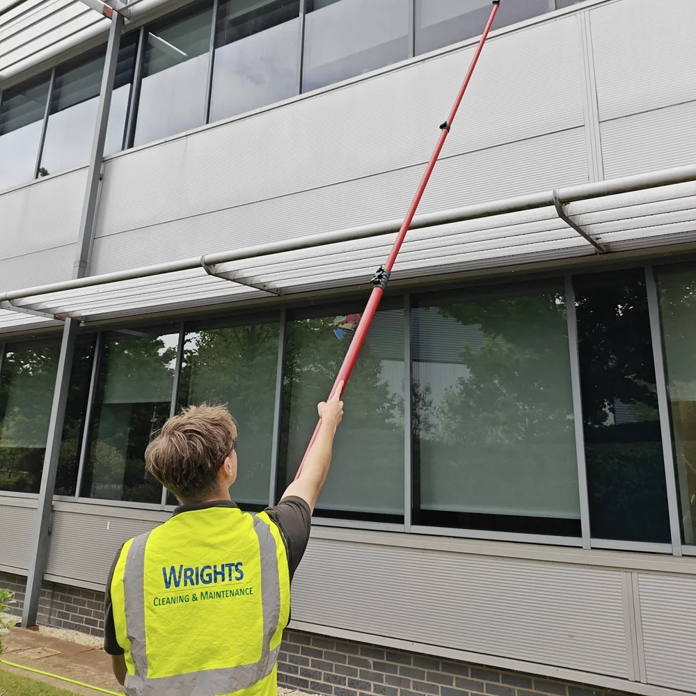Operative reaching second-floor office windows with a water-fed pole