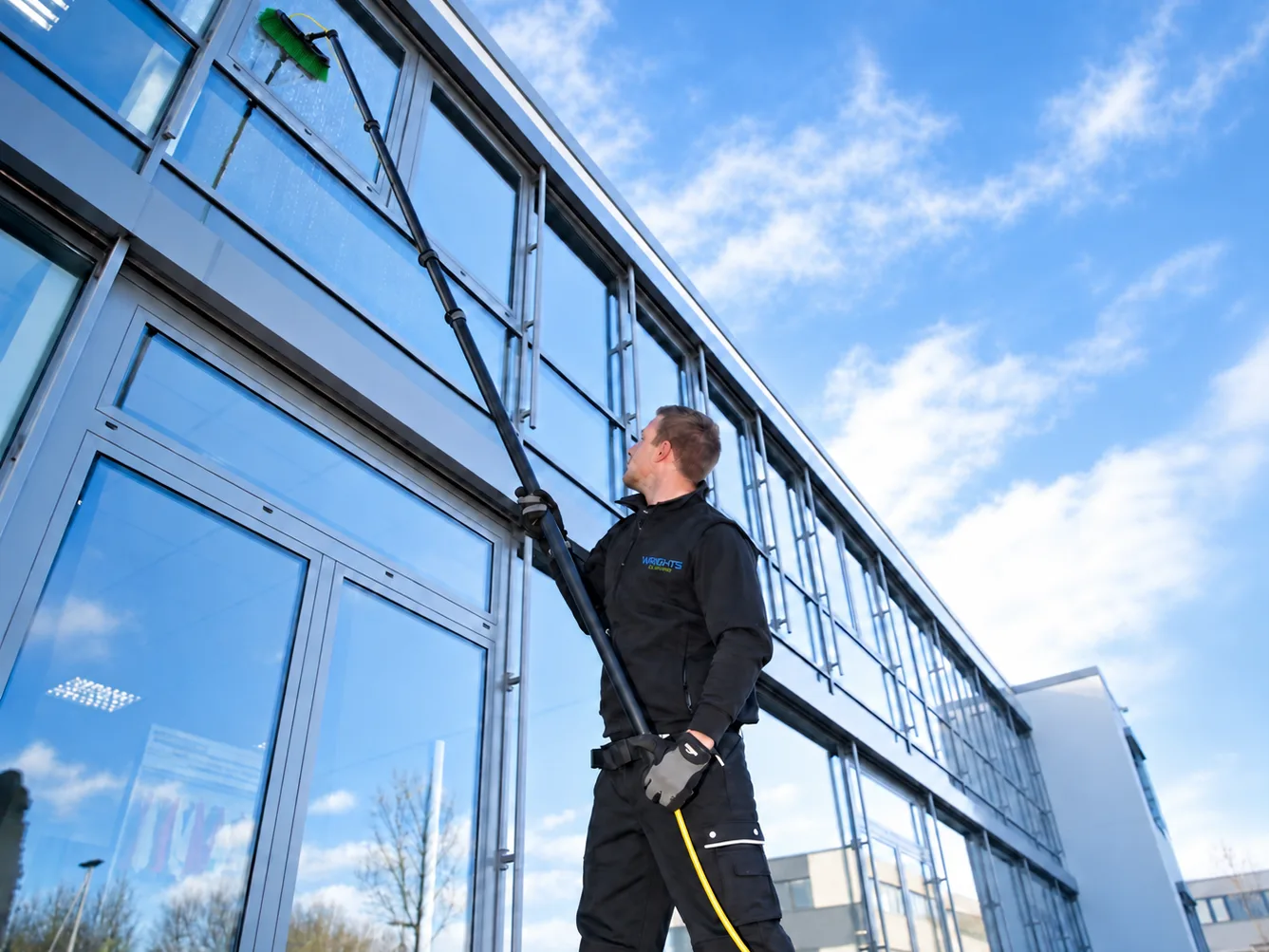 Water-fed pole cleaning the upper windows of a glass-fronted office